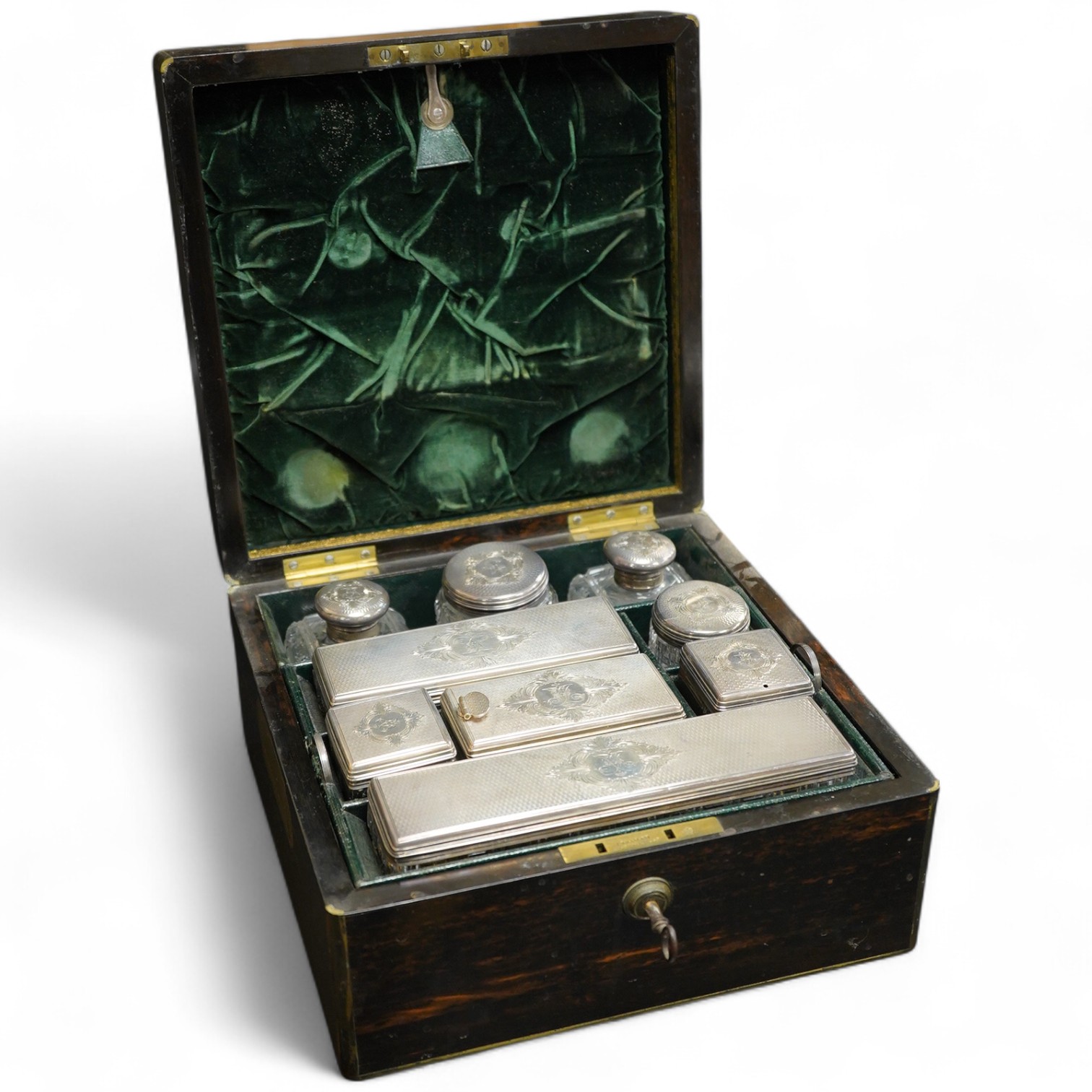 A Victorian brass mounted coromandel wood travelling toilet box, containing nine engine turned silver mounted cut glass toilet jars, with engraved initial, Brownett & Rose, London, 1870, the box of square form, with inse